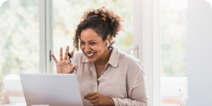 Woman smiling and waving at someone during a video call