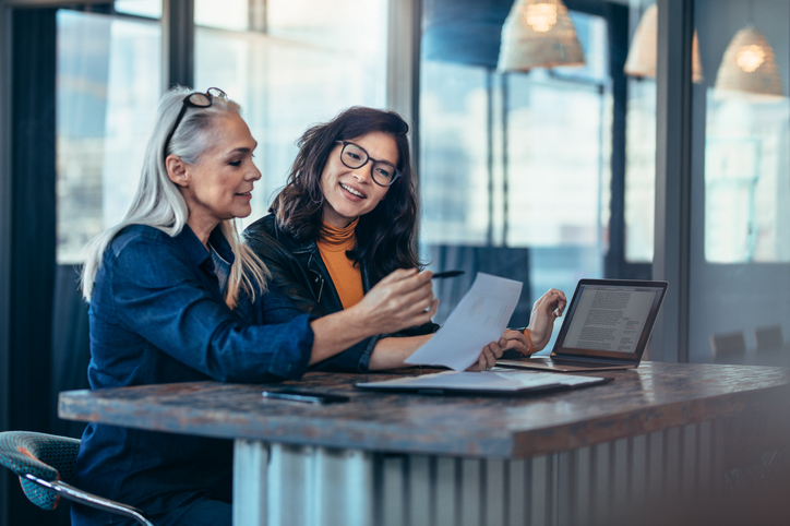 two women sitting at a table reviewing the same document