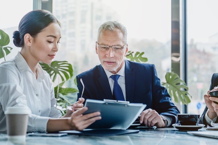 two individuals reviewing a document on a clipboard